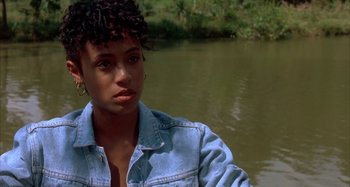 Movie still from “Jason's Lyric” (1994), directed by Doug McHenry – A woman with a denim jacket standing next to a body of water; Close Up shot, High angle