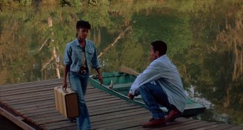 Movie still from “Jason's Lyric” (1994), directed by Doug McHenry – A man kneeling on a dock with a woman holding a briefcase; Wide shot, High angle