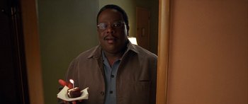 Movie still from “Johnson Family Vacation” (2004), directed by Christopher Erskin – A man holding a piece of cake in a room; Close Up shot, High angle