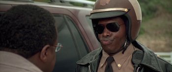 Movie still from “Johnson Family Vacation” (2004), directed by Christopher Erskin – A man in a uniform and a hat and sunglasses; Close Up shot, Low angle
