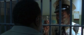 Movie still from “Johnson Family Vacation” (2004), directed by Christopher Erskin – A man holding a cell phone in front of a jail cell; Close Up shot, Over the shoulder angle