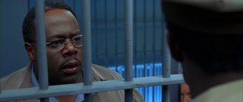 Movie still from “Johnson Family Vacation” (2004), directed by Christopher Erskin – A man sitting in front of a jail cell behind bars; Close Up shot, High angle