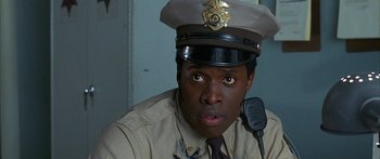Movie still from “Johnson Family Vacation” (2004), directed by Christopher Erskin – A police officer is sitting in front of a microphone; Close Up shot, Low angle