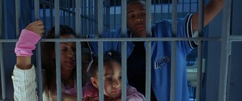Movie still from “Johnson Family Vacation” (2004), directed by Christopher Erskin – A group of people behind a metal fence; Medium shot, High angle
