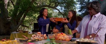 Movie still from “Johnson Family Vacation” (2004), directed by Christopher Erskin – A group of people standing around a table with plates of hot dogs; Medium shot, High angle