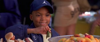 Movie still from “Johnson Family Vacation” (2004), directed by Christopher Erskin – A young boy wearing a hat and holding a piece of food in his hand; Close Up shot, High angle