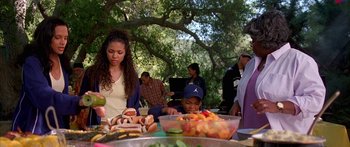 Movie still from “Johnson Family Vacation” (2004), directed by Christopher Erskin – A group of people standing around a table with food on top of it; Medium shot, High angle