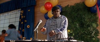 Movie still from “Johnson Family Vacation” (2004), directed by Christopher Erskin – A man wearing a hat is standing at a microphone; Medium shot, Low angle