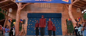 Movie still from “Johnson Family Vacation” (2004), directed by Christopher Erskin – A group of people standing on a stage in front of a banner; Wide shot, Low angle