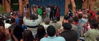 Movie still from “Johnson Family Vacation” (2004), directed by Christopher Erskin – A group of people standing on a stage with hands in the air; Wide shot, High angle