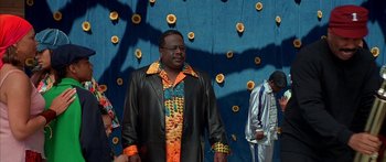 Movie still from “Johnson Family Vacation” (2004), directed by Christopher Erskin – A man in a leather jacket standing in front of a wall of sunflowers; Medium shot, Low angle