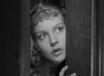 Movie still from “Kings Row” (1942), directed by Sam Wood – A black - and - white photo of a woman peeking out from behind a wooden wall; Close Up shot, Low angle