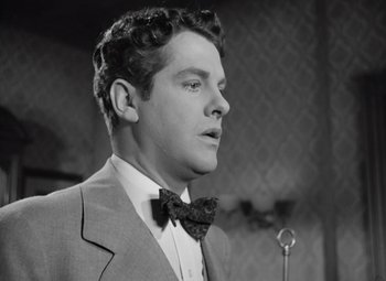 Movie still from “Kings Row” (1942), directed by Sam Wood – A black and white photo of a man wearing a suit and bow tie; Close Up shot, Low angle