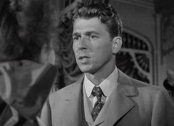 Movie still from “Kings Row” (1942), directed by Sam Wood – A man wearing a suit and tie in front of a mirror; Close Up shot, Over the shoulder angle