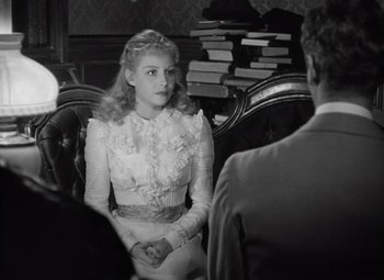 Movie still from “Kings Row” (1942), directed by Sam Wood – A woman in a white dress sitting in a chair; Medium shot, Over the shoulder angle