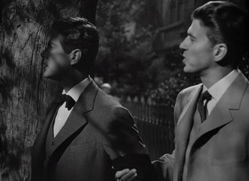 Movie still from “Kings Row” (1942), directed by Sam Wood – Two men in suits stand next to a tree; Close Up shot, Over the shoulder angle