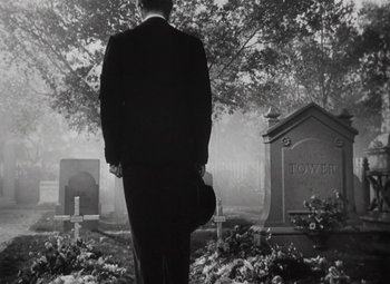 Movie still from “Kings Row” (1942), directed by Sam Wood – A man standing in front of a grave in a cemetery; Wide shot, Low angle