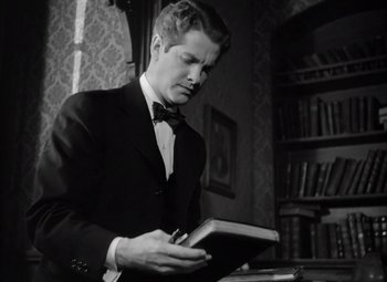 Movie still from “Kings Row” (1942), directed by Sam Wood – A black and white photo of a man reading a book; Close Up shot, Low angle
