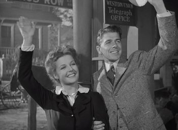 Movie still from “Kings Row” (1942), directed by Sam Wood – A man and a woman waving at the camera; Medium shot, Low angle