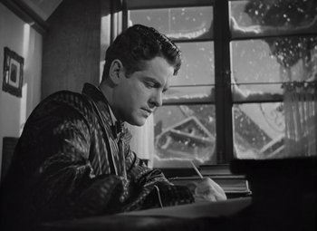 Movie still from “Kings Row” (1942), directed by Sam Wood – A young man writing on a piece of paper in front of a window; Medium shot, Low angle