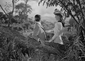 Movie still from “Kings Row” (1942), directed by Sam Wood – Two people are sitting on a tree branch; Wide shot, Low angle
