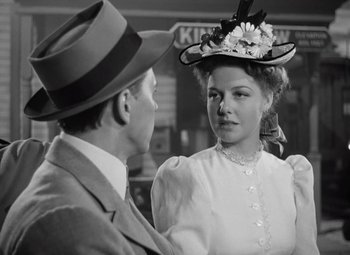 Movie still from “Kings Row” (1942), directed by Sam Wood – A man and a woman in a hat and dress; Close Up shot, Over the shoulder angle