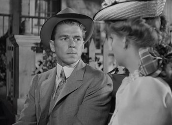Movie still from “Kings Row” (1942), directed by Sam Wood – A man in a suit and a woman in a hat; Medium shot, Over the shoulder angle