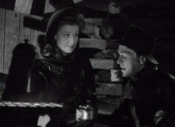 Movie still from “Kings Row” (1942), directed by Sam Wood – A man and a woman sitting next to each other in front of a brick wall; Medium shot, Low angle