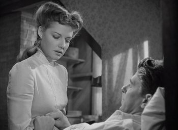 Movie still from “Kings Row” (1942), directed by Sam Wood – An old photo of a man and a woman in a room; Medium shot, Low angle