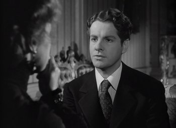 Movie still from “Kings Row” (1942), directed by Sam Wood – A black and white photo of a man in a suit and tie; Close Up shot, Over the shoulder angle