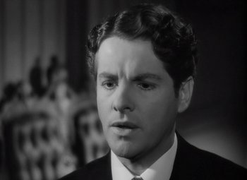 Movie still from “Kings Row” (1942), directed by Sam Wood – A black and white photo of a man in a suit and tie; Close Up shot, High angle