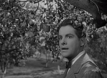 Movie still from “Kings Row” (1942), directed by Sam Wood – A black and white photo of a man standing under a fruit tree; Close Up shot, Low angle