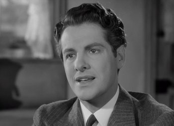 Movie still from “Kings Row” (1942), directed by Sam Wood – A man in a suit and tie looking at the camera; Close Up shot, Over the shoulder angle