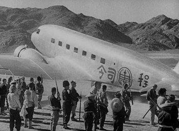 Movie still from “Lost Horizon” (1937), directed by Frank Capra – An old photo of people standing in front of an airplane; Extreme Wide shot, Low angle