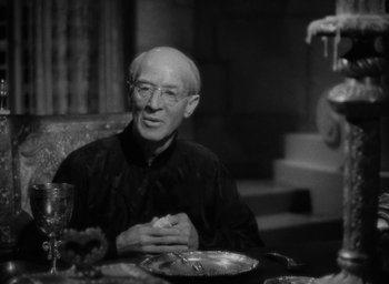 Movie still from “Lost Horizon” (1937), directed by Frank Capra – An older man sitting at a dinner table; Medium shot, Over the shoulder angle