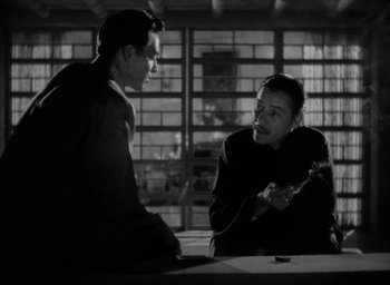 Movie still from “Lost Horizon” (1937), directed by Frank Capra – Two men sitting at a table talking to each other; Medium shot, Over the shoulder angle