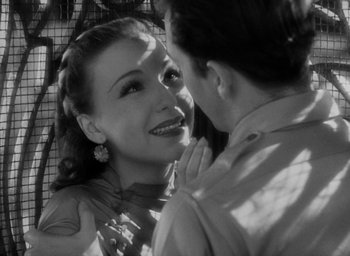 Movie still from “Lost Horizon” (1937), directed by Frank Capra – A woman smiles at the camera while a man looks on; Close Up shot, Over the shoulder angle
