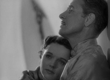 Movie still from “Lost Horizon” (1937), directed by Frank Capra – A man and a woman embracing each other in a black and white photo; Close Up shot, Low angle