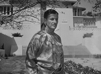 Movie still from “Lost Horizon” (1937), directed by Frank Capra – An older man wearing a silver jacket standing in front of a building; Medium shot, Low angle