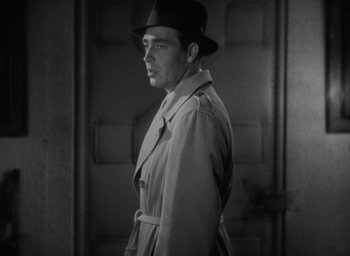 Movie still from “Lost Horizon” (1937), directed by Frank Capra – A black and white photo of a man wearing a hat and a trench coat; Close Up shot, Low angle