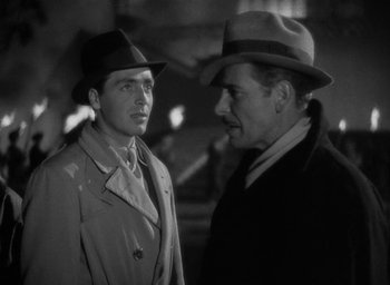 Movie still from “Lost Horizon” (1937), directed by Frank Capra – A man in a hat and a man in a trench coat and a hat; Close Up shot, Over the shoulder angle