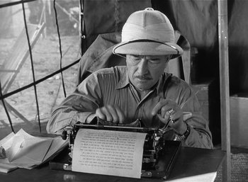 Movie still from “Mighty Joe Young” (1949), directed by Ernest B. Schoedsack – A man in a hat is typing on an old typewriter; Medium shot, High angle