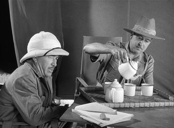 Movie still from “Mighty Joe Young” (1949), directed by Ernest B. Schoedsack – Two men sitting at a table drinking tea from white cups; Medium shot, High angle