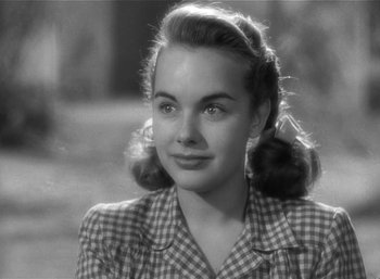 Movie still from “Mighty Joe Young” (1949), directed by Ernest B. Schoedsack – A young woman with pigtails is smiling for the camera; Close Up shot, Over the shoulder angle