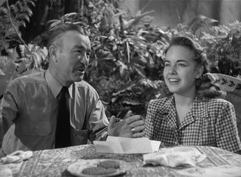 Movie still from “Mighty Joe Young” (1949), directed by Ernest B. Schoedsack – An old photo of a man and a woman sitting at a table; Medium shot, Over the shoulder angle
