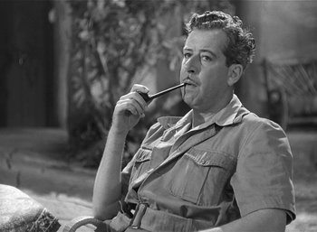 Movie still from “Mighty Joe Young” (1949), directed by Ernest B. Schoedsack – A man sitting on a chair with a pipe in his mouth; Close Up shot, High angle