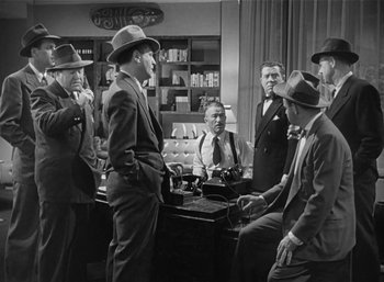Movie still from “Mighty Joe Young” (1949), directed by Ernest B. Schoedsack – A black and white photo of a group of men in suits and hats; Medium shot, High angle