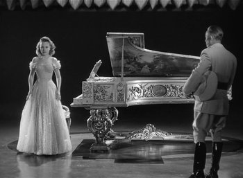 Movie still from “Mighty Joe Young” (1949), directed by Ernest B. Schoedsack – A man and a woman standing in front of an ornate piano; Wide shot, Low angle