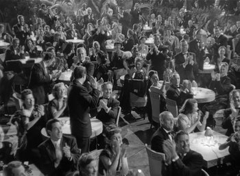 Movie still from “Mighty Joe Young” (1949), directed by Ernest B. Schoedsack – A group of people sitting at tables clapping and applauding; Extreme Wide shot, High angle