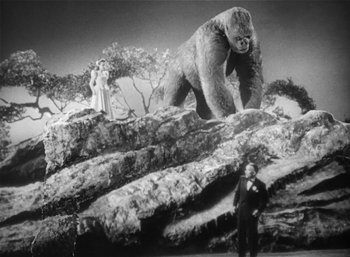 Movie still from “Mighty Joe Young” (1949), directed by Ernest B. Schoedsack – A man standing next to a gorilla and a woman; Extreme Wide shot, Low angle